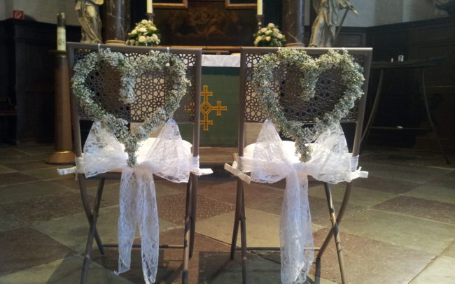 Hochzeit Blumendeko Herzen an Stühlen in der Kirche